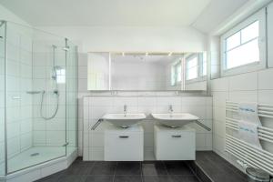 ein weißes Badezimmer mit zwei Waschbecken und einer Dusche in der Unterkunft Ferienhaus "Stella Olivia" in Lobbe