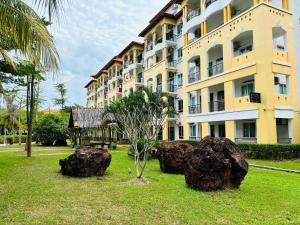 a building with rocks in the grass in front of it at Tiara Desaru By De Home in Bandar Penawar