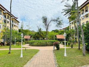 a walkway through a park with palm trees and buildings at Tiara Desaru By De Home in Bandar Penawar