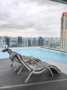 a lounge chair on the roof of a building with a pool at Brand New 2 bedroom near Paragon in Pratunam
