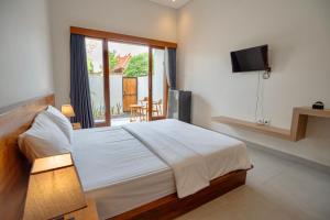 a bedroom with a large bed and a television at Abimanyu Guest House in Seminyak
