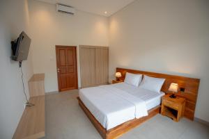 a bedroom with a white bed and a television at Abimanyu Guest House in Seminyak