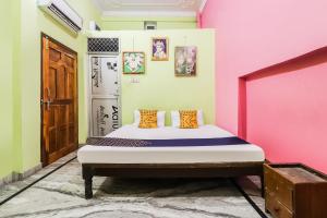 un letto in una stanza con pareti rosa e verdi di SPOT ON Maharani guest house a Ayodhya