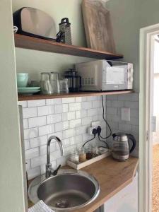 a kitchen counter with a sink and a microwave at Quaint Cottage Durban North in Durban