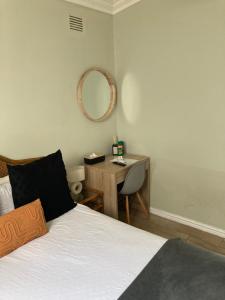a bedroom with a bed and a desk with a mirror at Quaint Cottage Durban North in Durban