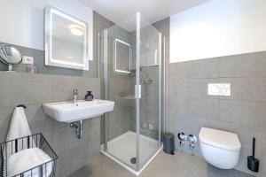a bathroom with a shower and a sink and a toilet at Stadtloft Penthouse "Eversten" Neubau Business Apartments für Projekt- und Firmenaufenthalte in Oldenburg +23 photos