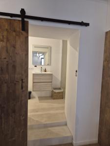 a bathroom with a wooden door and a sink at La Lanterne in Saint-Hippolyte