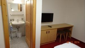 a bathroom with a sink and a desk with a television at Forsthaus Jehle in Sankt Anton am Arlberg