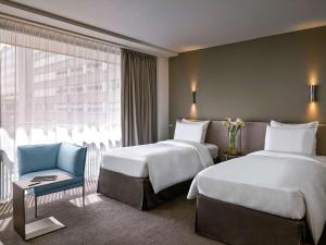Una habitación de hotel con dos camas y una silla azul. en Pullman Paris Tour Eiffel, en París 55 fotos más