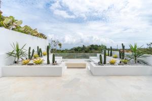a patio with three white planters filled with cactus at Casa Uluwatu - Ocean View Villa in Uluwatu