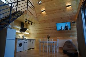 a kitchen with a table and a tv on a wall at your dream cottage in Ts'ikhisdziri
