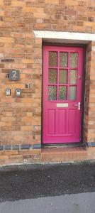 una puerta rosa en el lateral de un edificio de ladrillo en 2 Newcastle Street, en Crewe