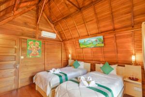 Dos camas en una habitación con paredes de madera. en Maha Nusa Menjangan, en Banyuwedang