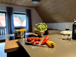 a cutting board with tomatoes and vegetables on a counter at Ferienwohnung am Brombachsee FeWo Horlacher in Pleinfeld +7 photos