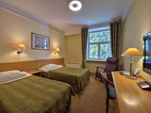 a hotel room with two beds and a desk at Barclay Hotel in Tartu