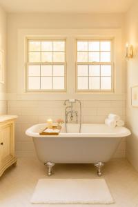 a white bath tub in a bathroom with two windows at Central Hollywood Homestay Getaway in Los Angeles