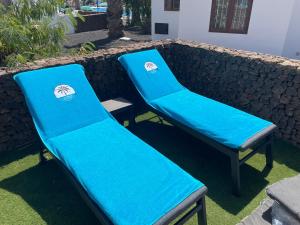 dos sillas azules sentadas junto a una pared de piedra en Las Brisas Villa 106, en Playa Blanca