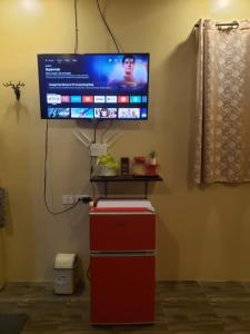 a flat screen tv on a wall above a red refrigerator at Portofhino South Homestay in Malitbog