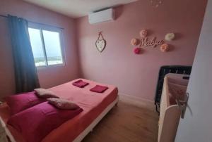 a pink bedroom with a bed and a window at Maison des Ramiers in Saint-Paul +2 photos