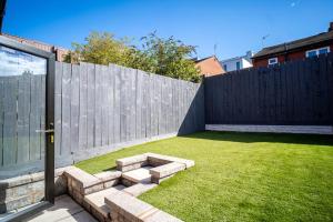 a backyard with a wooden fence and a lawn at The Scouse Suite in Liverpool