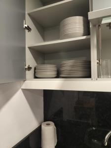 ポンテ・ダ・バルカにあるPegadinha House - Uchillの白いキャビネットに白い皿が置かれたキッチン