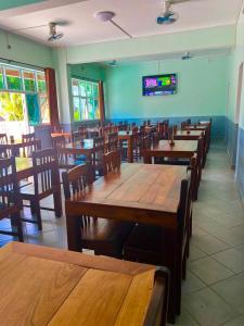 een restaurant met houten tafels en stoelen en een televisie bij Le Paradisier Hotel Restaurant in Antsohihy