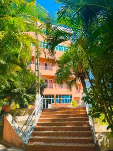 een trap die naar een roze gebouw met palmbomen leidt bij Le Paradisier Hotel Restaurant in Antsohihy +10 foto's