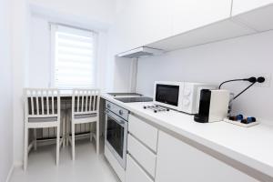 a white kitchen with a counter and a stove top oven at Lun Apartment in Cluj-Napoca