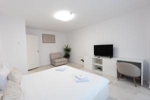 a white room with a bed and a desk and a tv at Lun Apartment in Cluj-Napoca