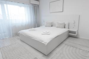 a white bedroom with a large white bed and a window at Lun Apartment in Cluj-Napoca