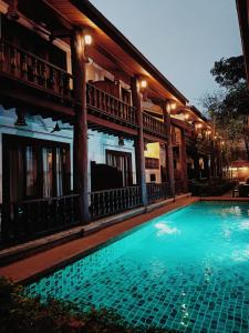a swimming pool in front of a building at night at Treasure Heritage Hotel in Luang Prabang