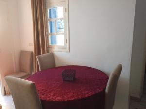 a red dining room table with chairs and a window at Jamila 2 in Al Maqārisah +7 photos