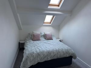 ein Schlafzimmer mit einem Bett mit zwei Kissen und zwei Fenstern in der Unterkunft City Centre top floor large flat in Sunderland