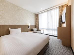 a hotel room with a bed and a tv at Nishitetsu Resort Inn Naha in Naha