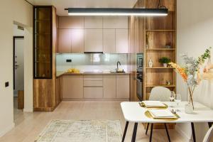 a kitchen with wooden cabinets and a white table at Auezov Apart in Almaty