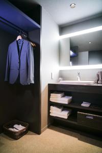 a bathroom with a sink and a robe hanging on a wall at KIORI Hotel Higashino Toin in Kyoto