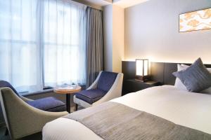 a hotel room with a bed and chairs and a window at KIORI Hotel Higashino Toin in Kyoto