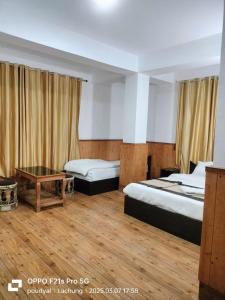 a hotel room with two beds and a table at lachung Bliss-Inn Hotel in Lachung
