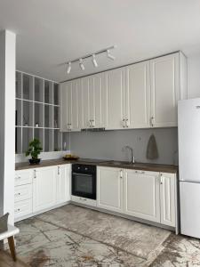 a white kitchen with white cabinets and a refrigerator at City View Prishtina in Pristina
