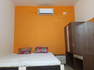 ein Schlafzimmer mit einem Bett mit einer orangefarbenen Wand in der Unterkunft Bhedaghat resort in Bherāghāt