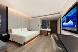 Un dormitorio con una cama y un televisor de pantalla plana. en Atour Hotel Shenzhen CBD Futian Metro Station, en Shenzhen
