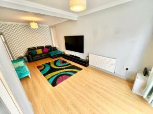 a living room with a couch and a tv at Labbyf Spacious 3-4 Bed House Sleeps 8 near Northampton Train Station, University and City Centre in Northampton