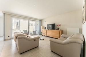ein Wohnzimmer mit zwei Sofas und einem Fernseher in der Unterkunft Apartment La Dune Blanche - Ontspannen in Bredene in Bredene