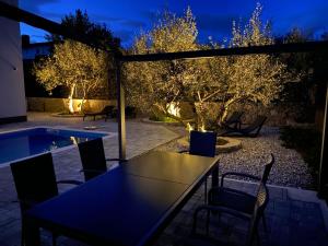 a table and chairs on a patio at night at Villa Lio mit Pool in Linardići