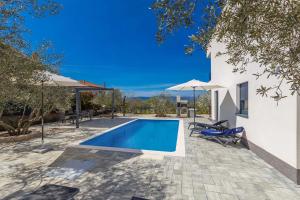 a swimming pool with chairs and umbrellas next to a house at Villa Lio mit Pool in Linardići