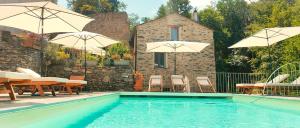 ein Schwimmbad mit Sonnenschirmen, Tischen und Stühlen in der Unterkunft Stalla in Ortiporio
