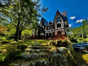una grande casa su una collina con delle rocce di fronte di HAKUBA GARDEN Hotel a Hakuba