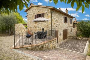 a stone building with a table and an umbrella at Oliveto Del Cantarello in Chiusi
