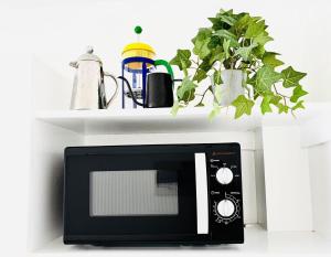 a black microwave sitting on a shelf with plants at Studio By The Sea in Dumaguete
