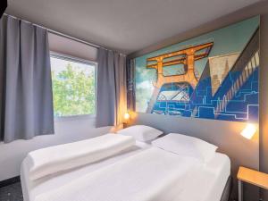 a bedroom with two beds and a painting on the wall at B&B HOTEL Würzburg-Ost in Würzburg